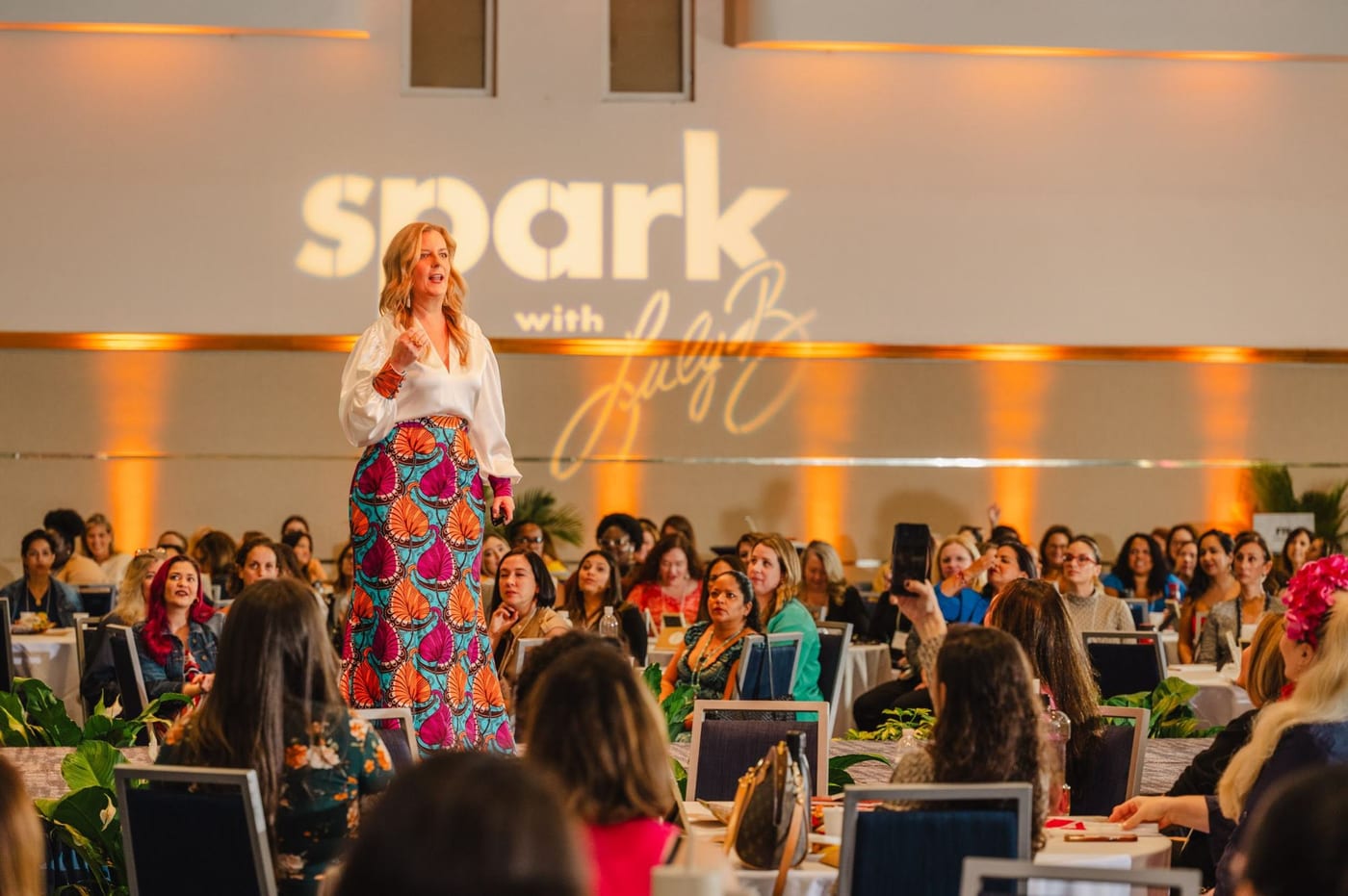 Luly B. speaking on stage at SPARK in front of a full room